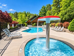 A swimming pool with a water fountain, lounge chairs, and a wooden building in the background. - Mountain Lookout – Incredible Mt. LeConte Views, Theater, Game Room, Sauna & Hot Tub (Gatlinburg)