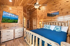 A wooden cabin room with a bed, a dresser, a television, and a ceiling fan. - Mountain Lookout – Incredible Mt. LeConte Views, Theater, Game Room, Sauna & Hot Tub (Gatlinburg)