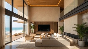 Un salon moderne doté d’un grand téléviseur, de sièges confortables et offrant une vue sur la plage.