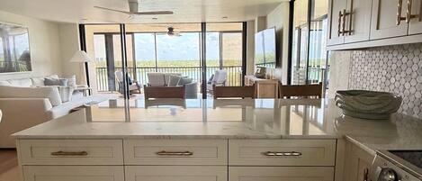 Una cocina amplia con una isla grande, electrodomésticos modernos y vistas a un balcón.