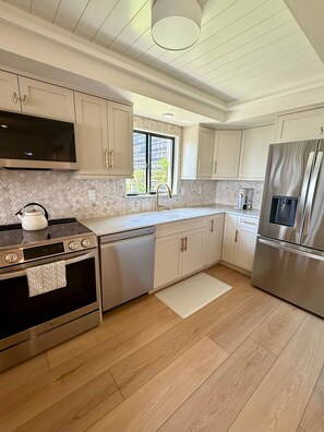 A modern kitchen with stainless steel appliances, a large window, and a view of greenery outside. - Newly Renovated 2 Bedroom Condo across the street from the Beach (Bonita Springs)