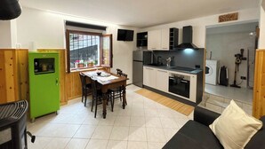 Una cucina compatta con zona pranzo, frigorifero verde e divano nero.