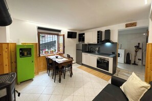 A compact kitchen with a dining area, a green refrigerator, and a black sofa. - Mountain Home, 6 minutes from the cable car, pets allowed, up to 4 guests. (Chiesa In Valmalenco)
