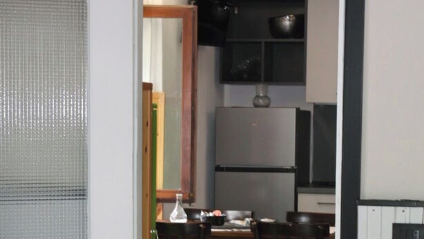Una stanza con tavolo da pranzo, sedie, frigorifero e televisione.