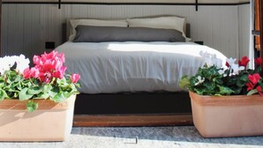 Una camera da letto con un letto, due comodini, una testiera e due piante in vaso.