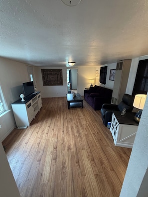 A compact living space with a kitchenette, a sofa, a small table, and a television.