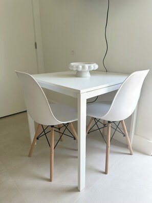 A white dining table with four chairs, a white bowl on the table, and a black cable on the wall. - Casita Near Little Havana with Parking (Miami)
