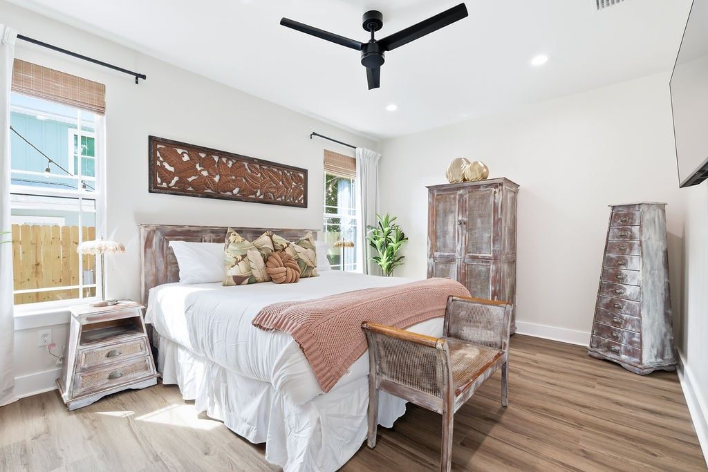 A bedroom with a bed, a chair, a wardrobe, and a ceiling fan.