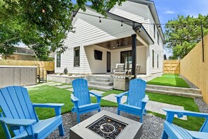 A house with a covered patio, outdoor seating, and a fire pit. - Pool, Sleeps 16, Outdoor Fun, Golf Cart, Fire Pit (Panama City Beach)
