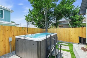 A backyard with a wooden fence, a hot tub, and a tree. - Pool, Sleeps 16, Outdoor Fun, Golf Cart, Fire Pit (Panama City Beach)