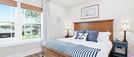 Un dormitorio con una cama de madera, dos mesitas de noche, un ventanal con persianas y un cuadro enmarcado en la pared.