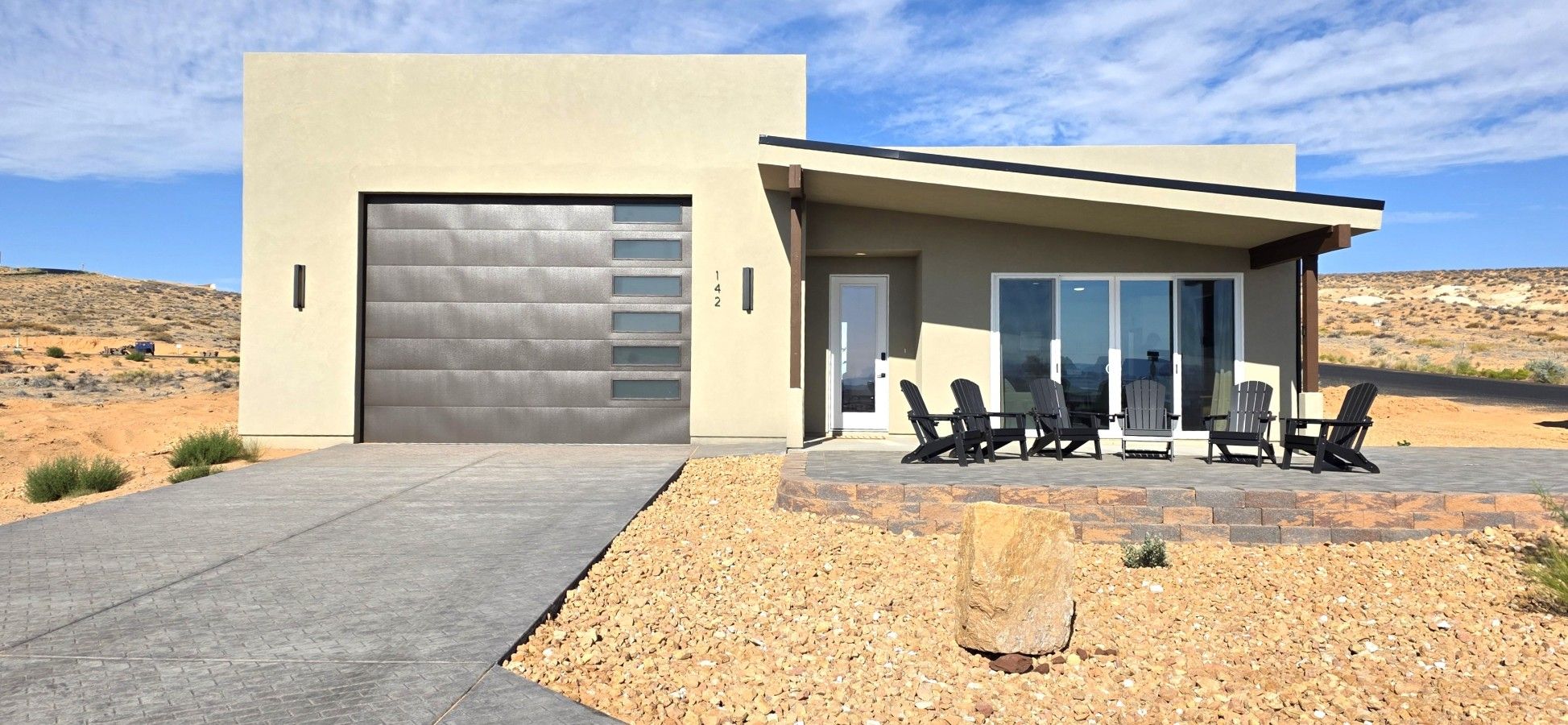 Een modern gebouw met garage, terras en een woestijnlandschap.