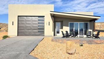 Een modern gebouw met garage, terras en een woestijnlandschap.