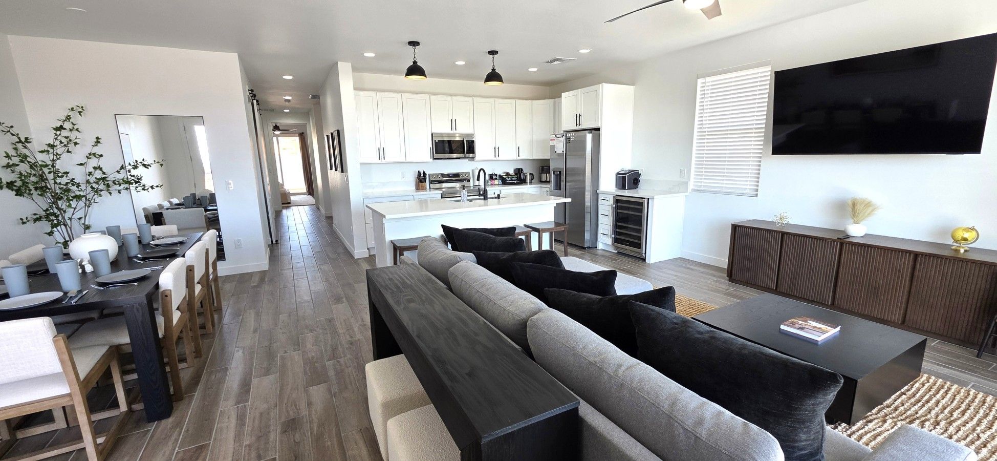 A modern kitchen with white cabinets, a central island, and a dining area with a long table and chairs.