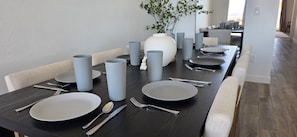 Ein Esstisch mit Geschirr, Besteck und grauen Gläsern in einem modernen Ambiente.