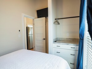 Ein Schlafzimmer mit einem Bett, einem Kleiderschrank, einem Spiegel und einer Hängeleuchte.