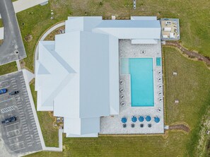 Ein Blick von oben auf ein Gebäude mit Schwimmbad, Sitzgelegenheiten im Freien und einem Parkplatz.