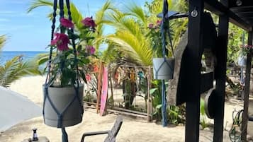 Eine Terrasse am Strand mit Sitzgelegenheiten im Freien, einer hängenden Pflanze und Blick auf den Ozean.