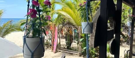 A beachside patio with outdoor seating, a hanging plant, and a view of the ocean.