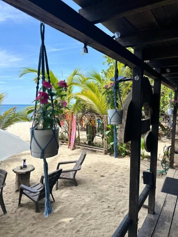 A beachside patio with outdoor seating, a hanging plant, and a view of the ocean. - Eco Hostal Paraiso (Santa Marta)