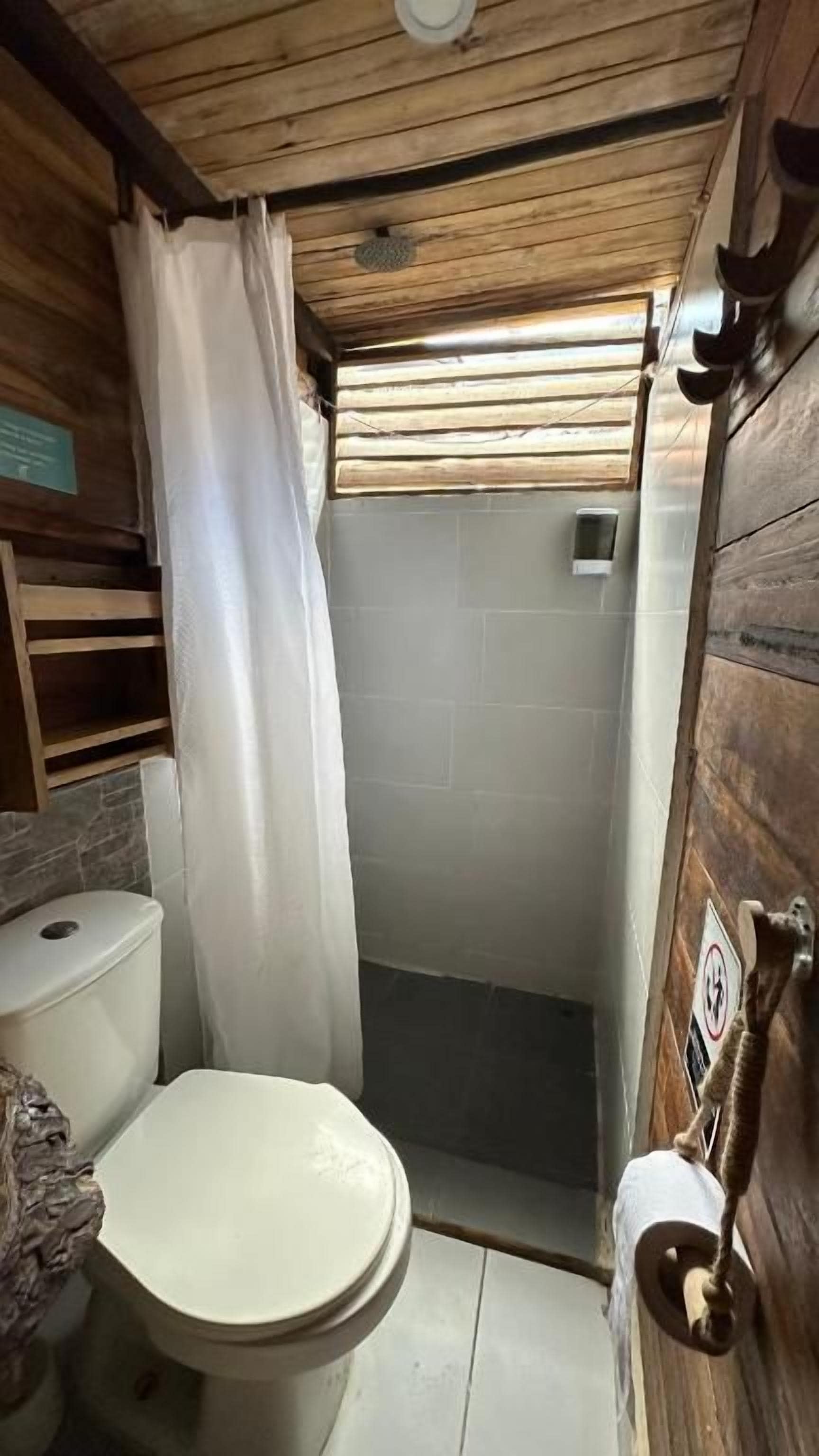 Une petite salle de bain avec des toilettes, une douche et des murs en bois.