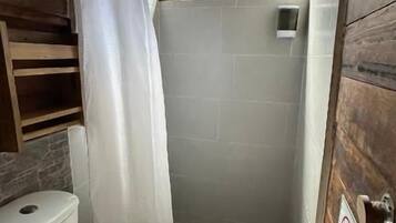 Une petite salle de bain avec des toilettes, une douche et des murs en bois.