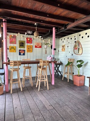 A wooden dining area with a table and chairs, a hanging light fixture, and a wall decorated with various framed pictures.