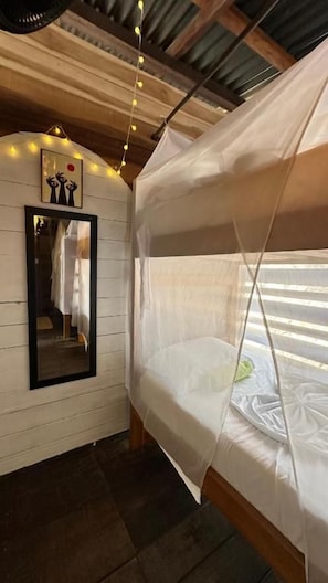 Una cama litera con dosel, un espejo en la pared y luces colgantes.