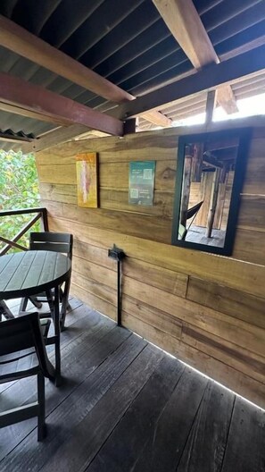 Una cabaña de madera con una mesa y sillas en el porche, techo de madera y una ventana con vistas.