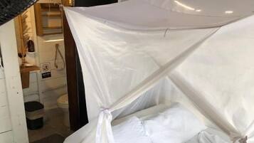 A bed with a canopy, a blue towel, and a white pillow.