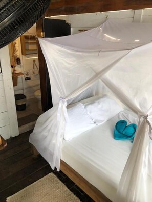 A bed with a canopy, a blue towel, and a white pillow.