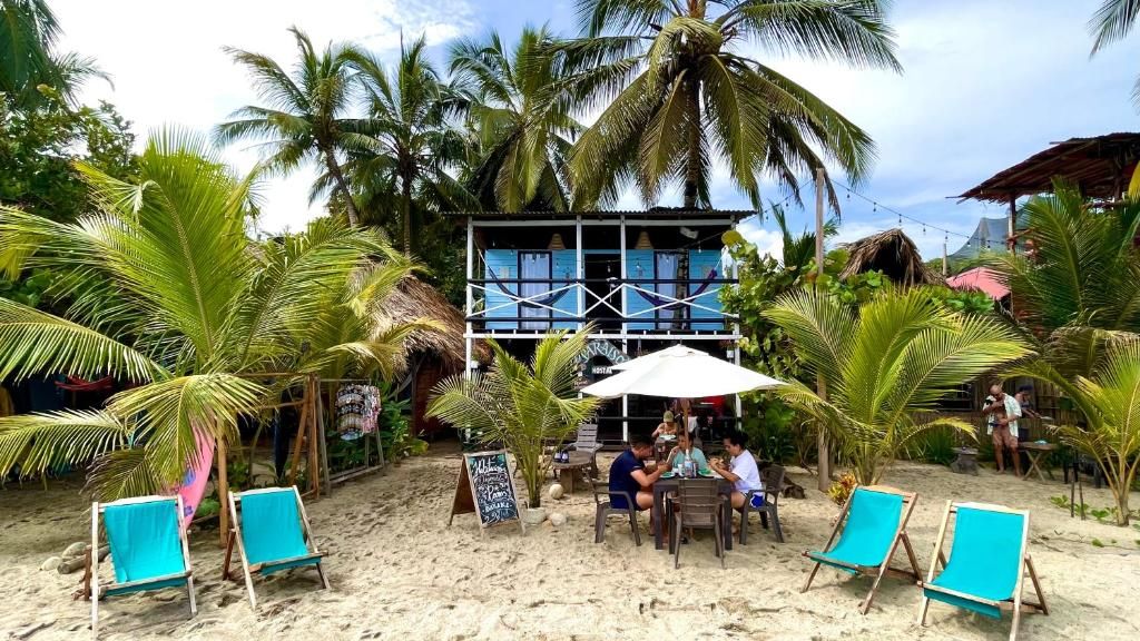 A beachside restaurant with outdoor seating, palm trees, and a building with a blue facade.