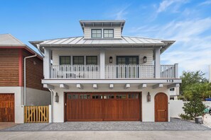 Ein zweistöckiges Haus mit Balkon und Garage, bewölkter Himmel.