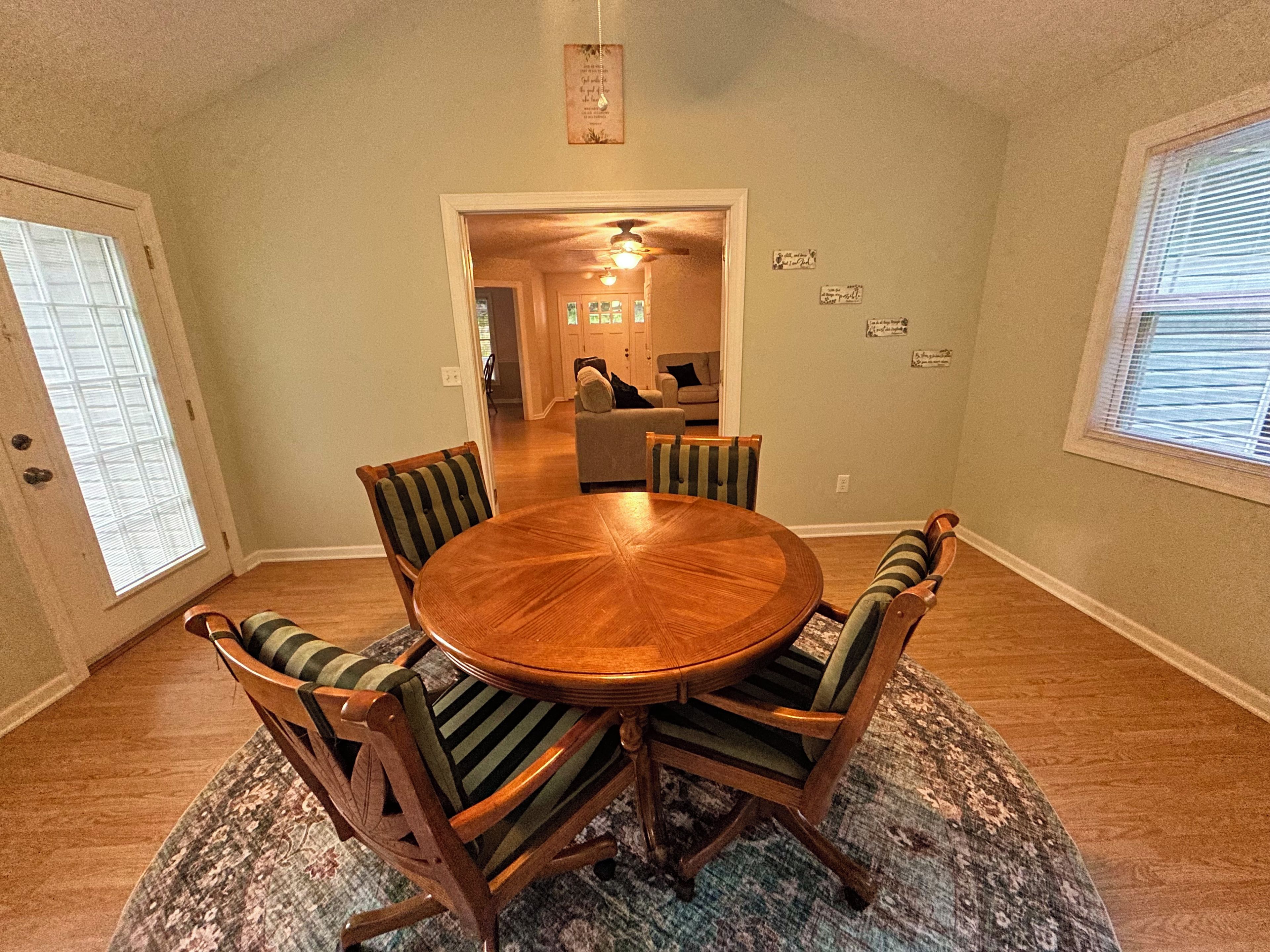 A dining area with a round wooden table surrounded by six chairs with striped cushions.