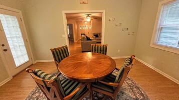 A dining area with a round wooden table surrounded by six chairs with striped cushions.