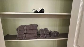 Ein Stauraum mit Regalen, auf denen Handtücher, ein Schuhpaar und Toilettenpapier liegen.