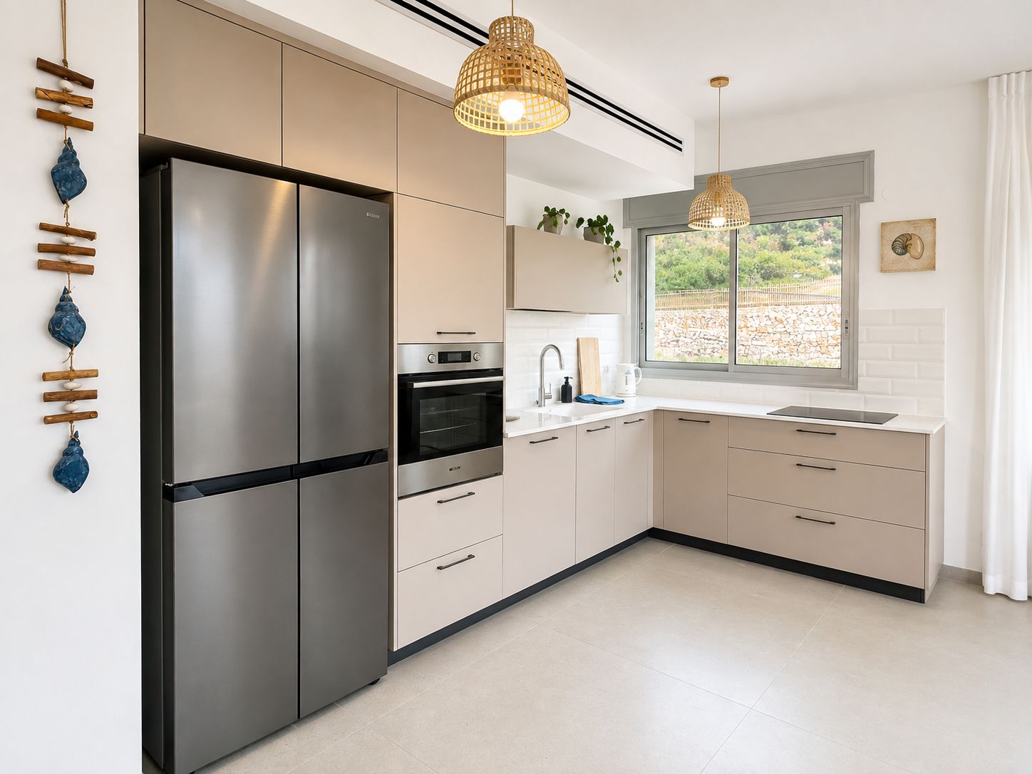 Una cocina moderna con un refrigerador de acero inoxidable, horno y microondas integrado. Hay dos lámparas colgantes, una ventana con vistas y un lavabo con encimera.