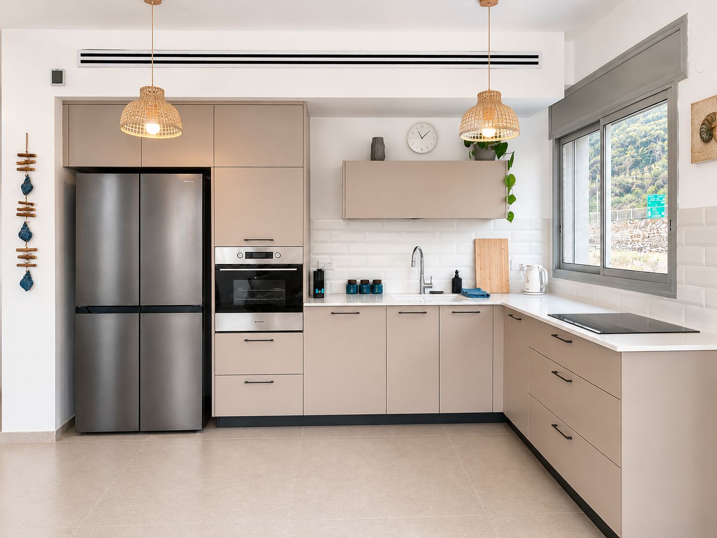 Cocina moderna con refrigerador de acero inoxidable, dos hornos y un lavamanos.