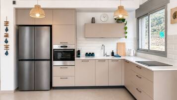 Cocina moderna con refrigerador de acero inoxidable, dos hornos y un lavamanos.