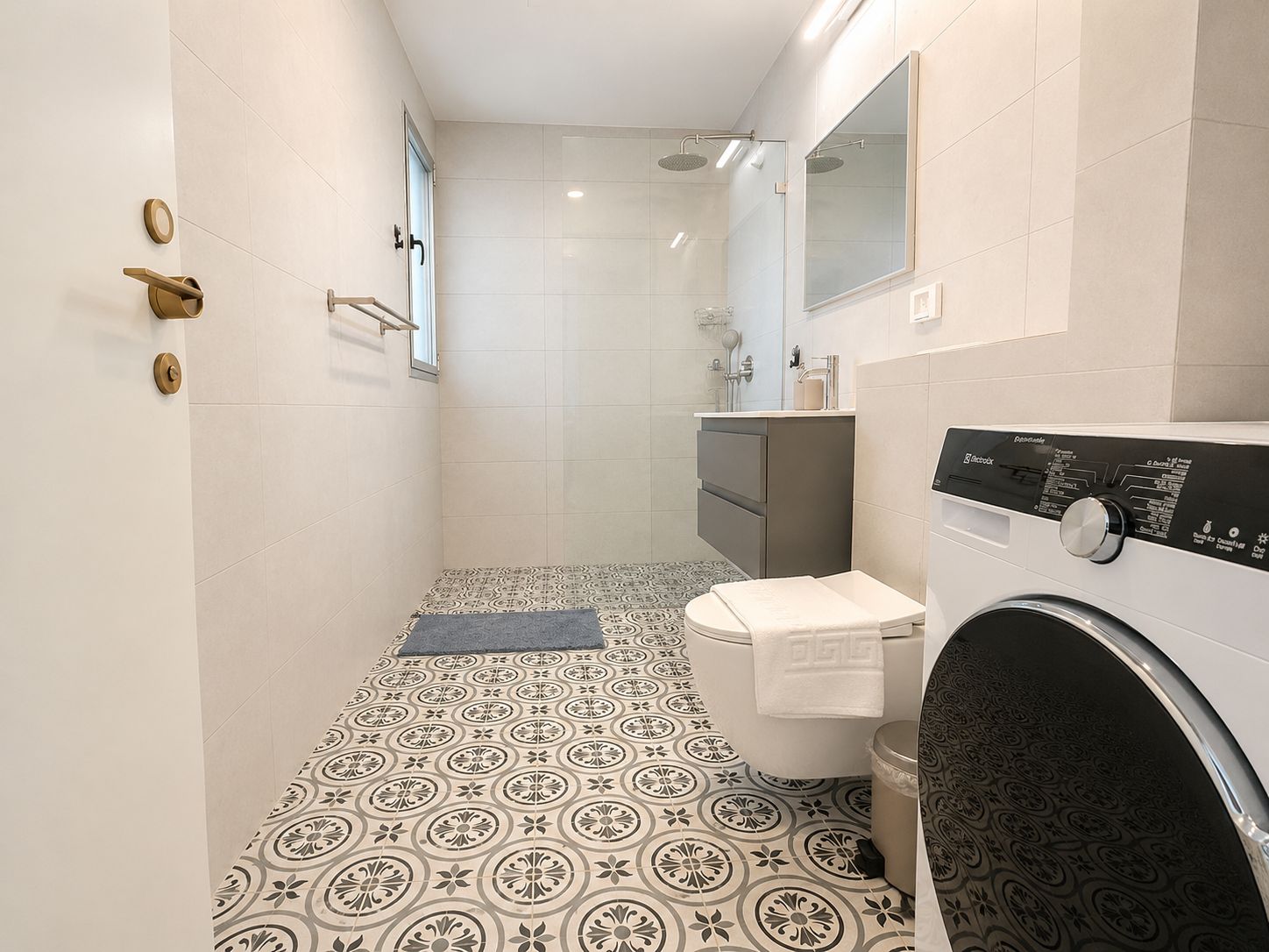 Un baño moderno con piso estampado, inodoro, lavadora y ducha.