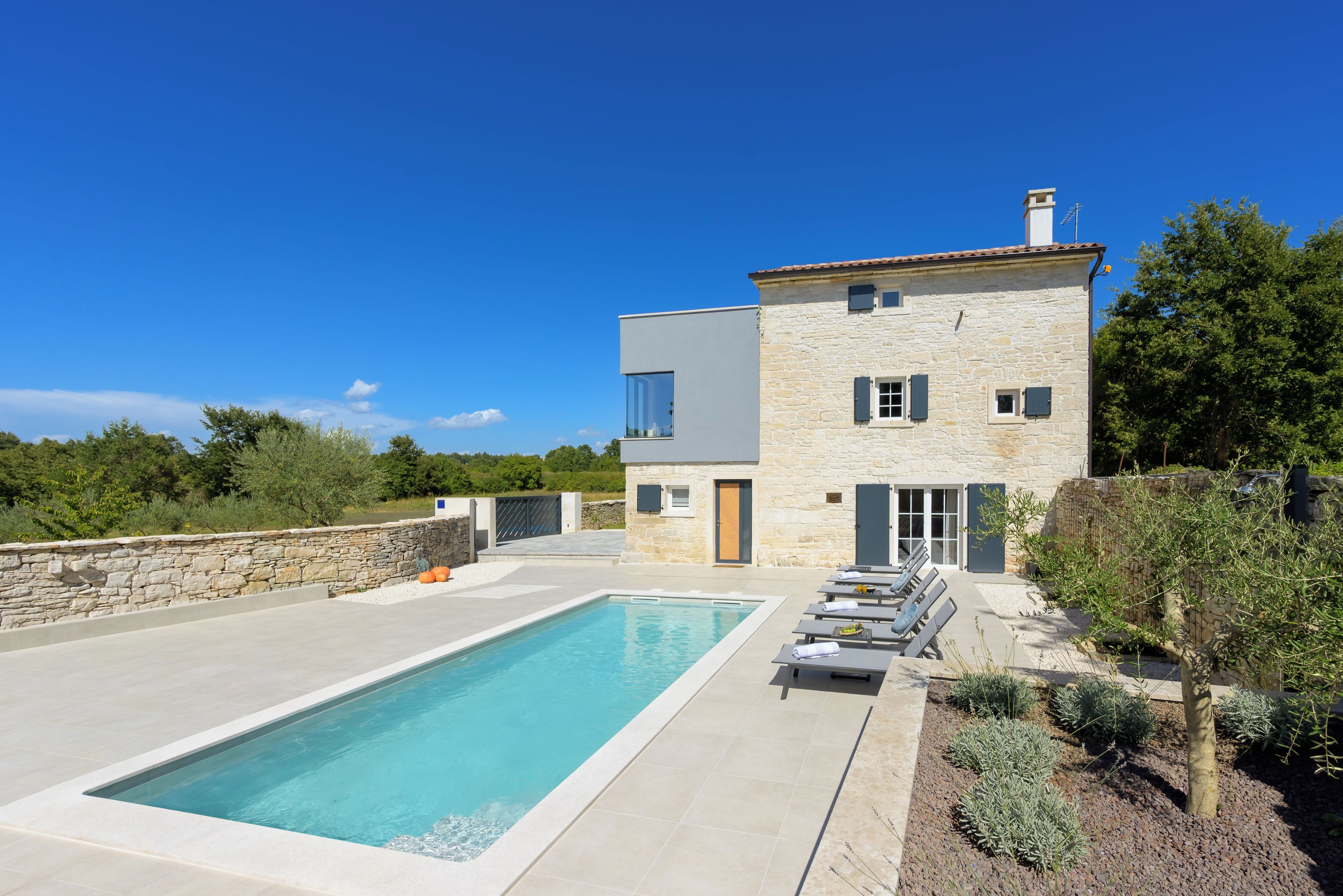 A modern two-story house with a swimming pool and outdoor seating.