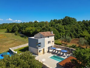 Un bâtiment en pierre de deux étages, doté d’une piscine et d’un espace extérieur aménagé pour s’asseoir.