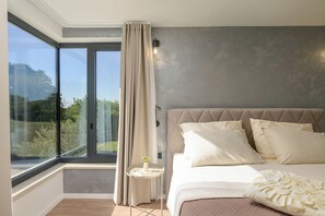 A bedroom with a large window, a bed with multiple pillows, and a small bedside table with a vase. - Villa Merklin (Istria - Debeljuhi) (Debeljuhi)