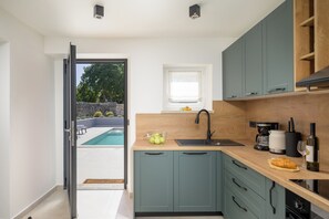 A modern kitchen with a built-in sink, wooden countertop, and teal cabinets. - Villa Merklin (Istria - Debeljuhi) (Debeljuhi)