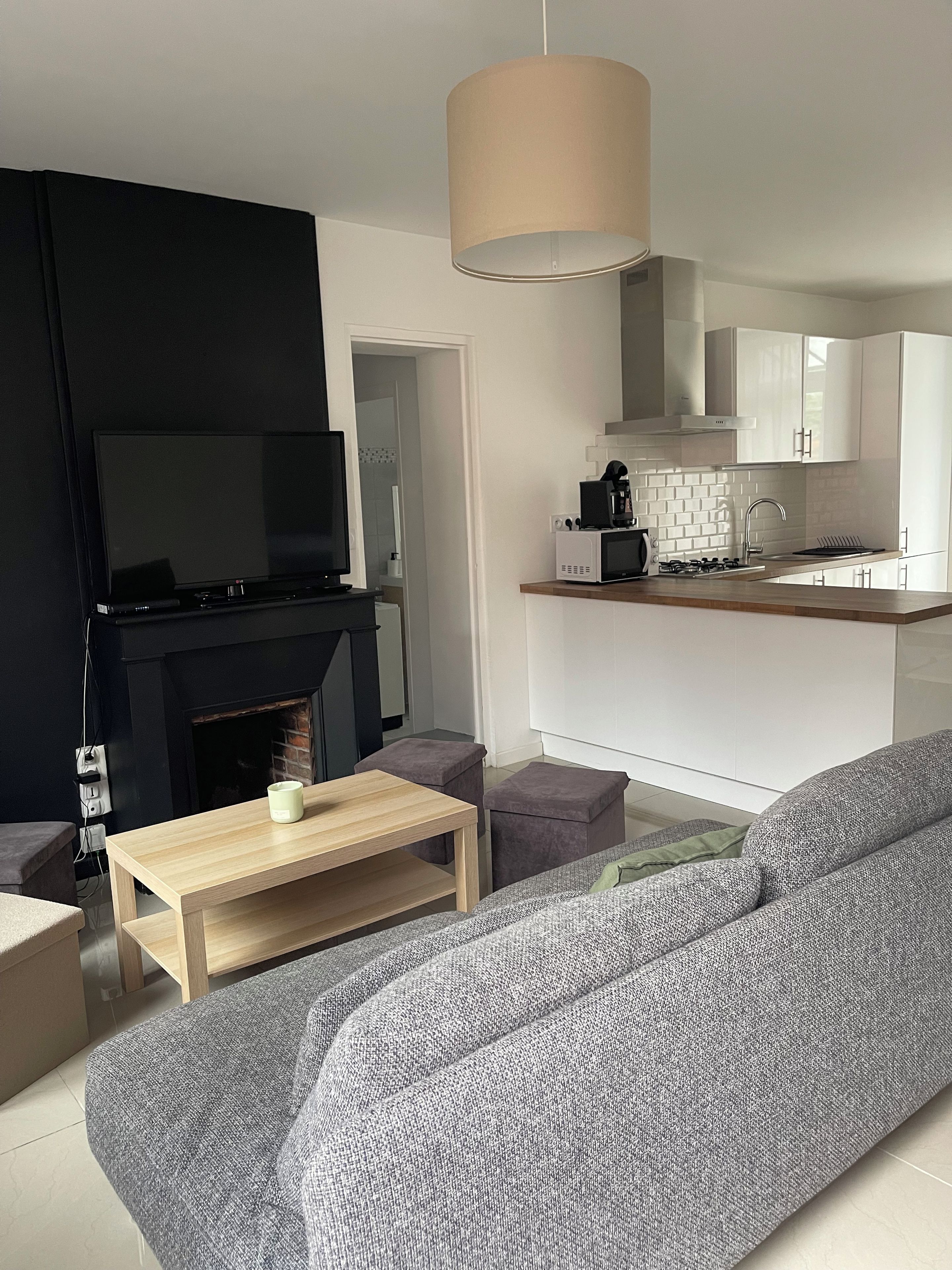 Een moderne woonkamer met een flatscreen televisie, een open haard, een bank en een houten salontafel.