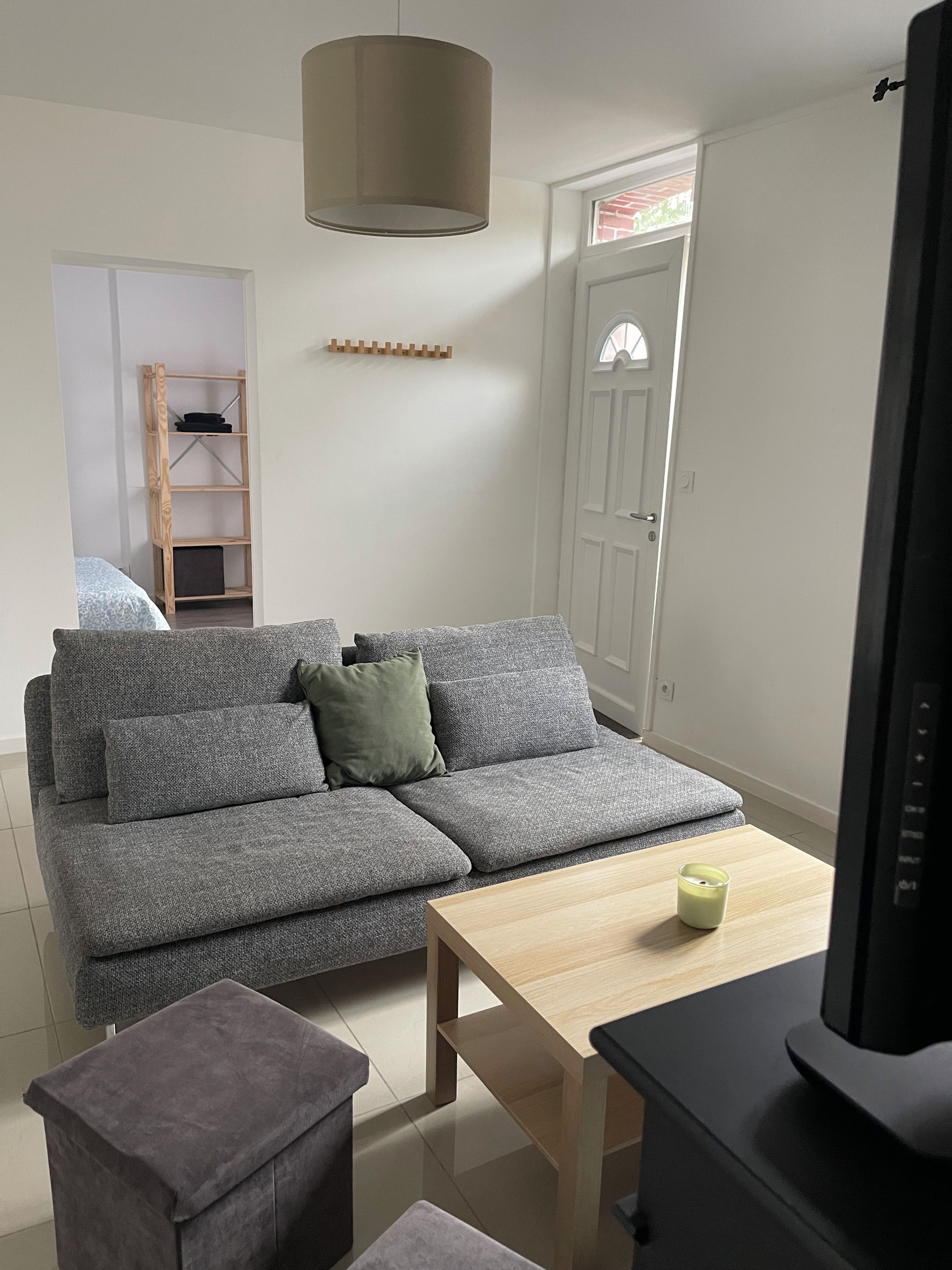 Un salon moderne avec un canapé d’angle gris, une table basse en bois et un téléviseur.