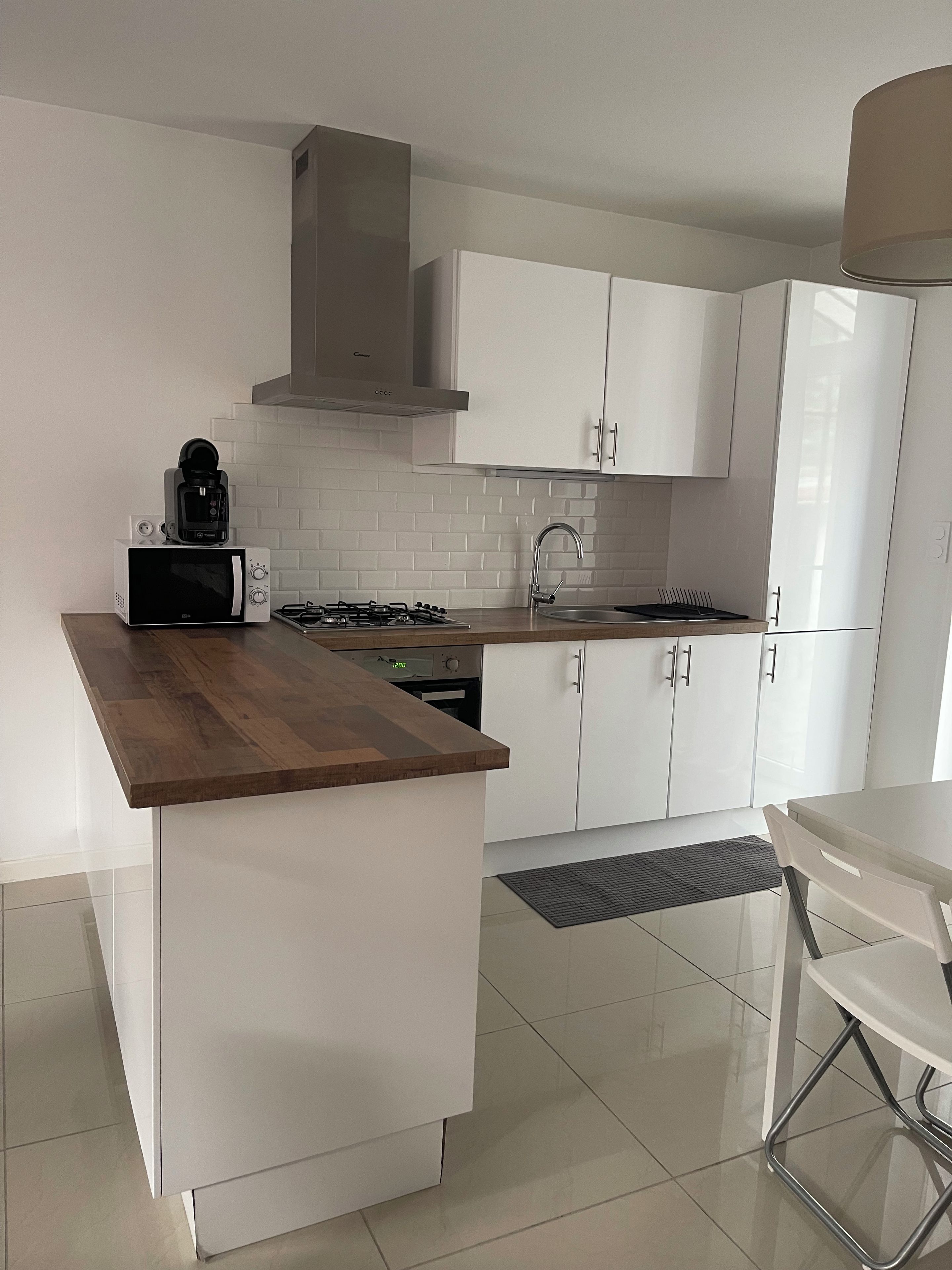 A modern kitchen with white cabinetry, a wooden countertop, a built-in microwave, a gas stove, and a sink.