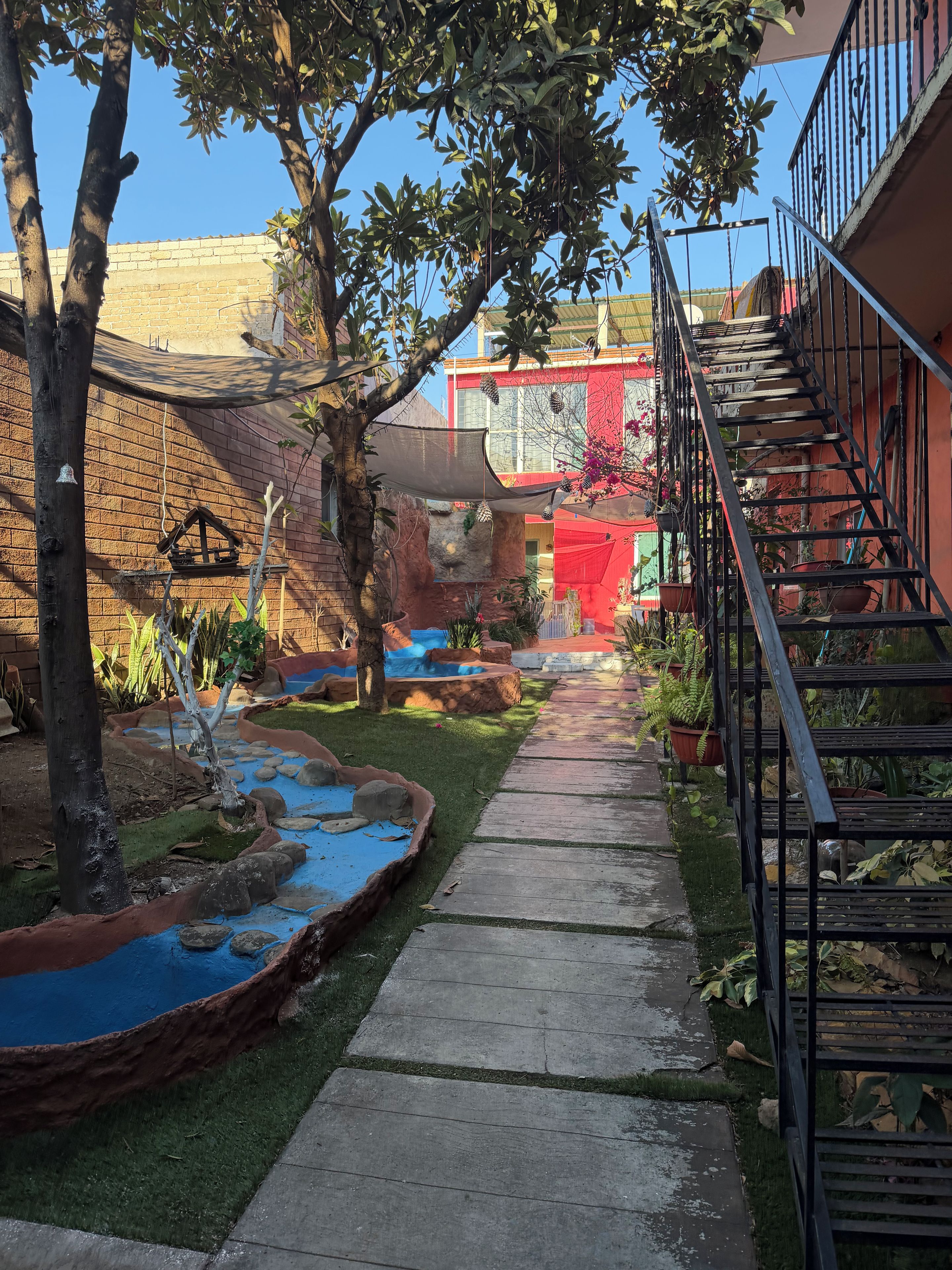 A courtyard with a brick wall, a small water feature, and a metal staircase.
