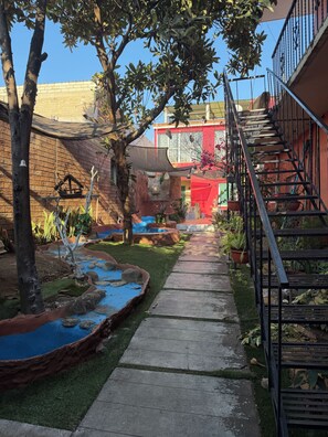 A courtyard with a brick wall, a small water feature, and a metal staircase. - CASA XCAANDA  (Oaxaca de Juárez)