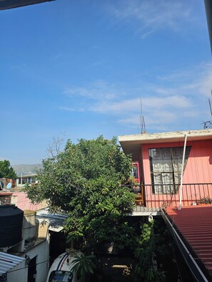 A residential area with a pink building, a tree, and a clear blue sky.